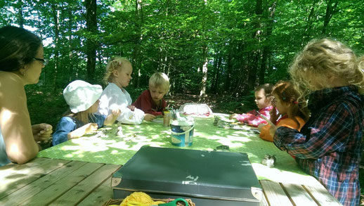 Kinder sitzen beim Basteln an einem Tisch.